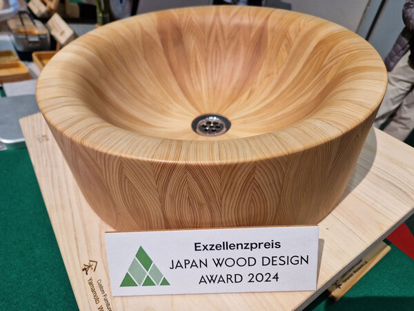 Foto von einem Holzwaschbecken auf dem Messestand. Davor steht ein Schild mit der Aufschrift: Exzellenzpreis Japan Wood Design Award 2024