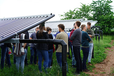 Studierende stehen in einer großflächigen Photovoltaikanlage