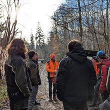 Studierende hören dem Referenten im Wald zu