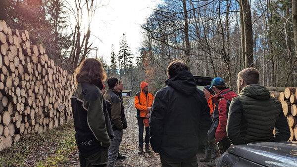 Studierende hören dem Referenten im Wald zu