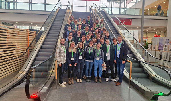 Gruppenfoto mit den Teilnehmern an einer Rolltreppe im Messegebäude