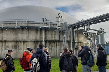 Studierende stehen in einer Gruppe vor einer Biogasanlage