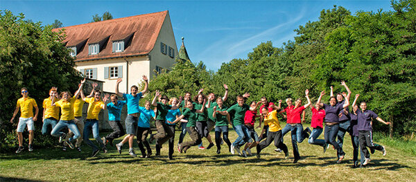 Studierende springen vor der Hochschule in die Luft und lachen