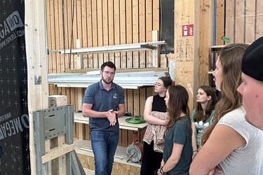Florian Hegar, Juniorchef von Holzhaus Bonndorf, erläutert den Rottenburger Studierenden den Wandaufbau eines modernen Holzfertigbaus.