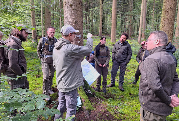 Die niederländischen Besucher stehen mit dem Referetnten im Wald