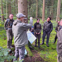 Die niederländischen Besucher stehen mit dem Referetnten im Wald